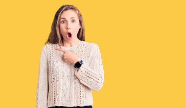 Gündelik süveter giyen genç ve güzel sarışın bir kadın parmaklarıyla yüzünü göstererek şaşırdı, ağzı açık hayret içinde kaldı.. 