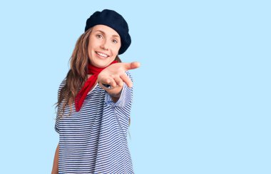 Fransız beresi ve çizgili tişört giyen genç, güzel, sarışın bir kadın. Gülümsüyor, avuç içi kadar yardım ve kabul görüyor.. 