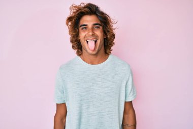 Günlük kıyafetler giyen genç İspanyol adam komik bir ifadeyle dilini dışarı çıkartıyor. duygu kavramı. 