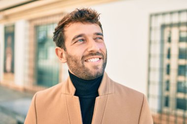 Zarif ceket giyen yakışıklı iş adamı dışarıda mutlu bir şekilde gülümsüyor.