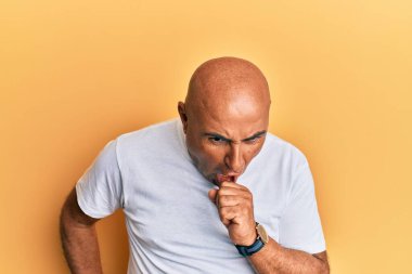 Olgun bir Orta Doğulu adam günlük beyaz tişört giyer kendini kötü hisseder ve soğuk algınlığı veya bronşitin belirtisi olarak öksürür. sağlık hizmeti kavramı. 