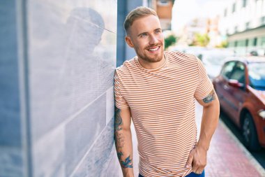 Genç İrlandalı gülümseyen mutlu adam şehrin duvarına yaslanıyor..