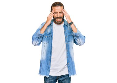 Uzun saçlı, sakallı, eli kafasında sıradan bir kot ceket giyen çekici bir adam. Stres yüzünden başı ağrıyor. migren ağrısı. 