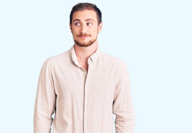 Genç, yakışıklı, beyaz, günlük kıyafetler giyen, gülümseyen, yan bakan ve düşünen bir adam.. 