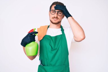 Önlük giyen genç yakışıklı adam, elinde spreyle gergin ve hayal kırıklığına uğramış, şaşırmış ve kızgın bir yüz. 