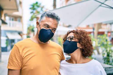 Coronavirus koruma maskesi takan orta yaşlı çift şehir caddesinde yürüyor..