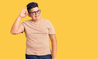 Günlük kıyafetler ve gözlük takan, gülümseyen küçük çocuk el ve parmaklarıyla 