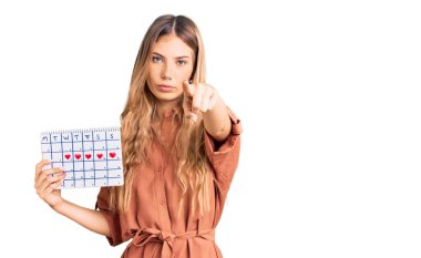 Güzel, beyaz bir kadın, sarı saçlı, kalp takvimiyle kamerayı işaret ediyor ve sen, kendinden emin, ciddi görünüyorsun. 