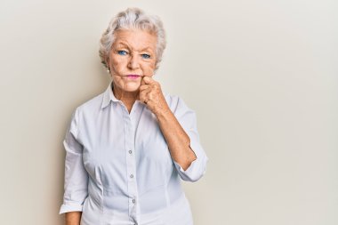 Kıdemli, gri saçlı, günlük kıyafetler giyen, şüpheyi düşünen, çenesinde parmak olan ve kafasını kaldırıp merak eden bir kadın. 