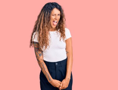 Dövmeli, beyaz tişörtlü, seksi bir ifadeyle kameraya bakan, neşeli ve mutlu yüzlü genç İspanyol kadın.. 