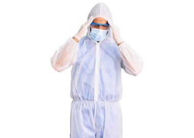 Doktor korumalı koronavirüs üniforması giyen genç İspanyol bir adam ve stresten dolayı başı ağrıyan bir tıbbi maske takıyor. migren ağrısı. 
