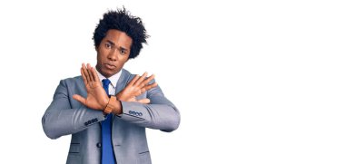 Afro saçlı, iş ceketi giyen yakışıklı Afro-Amerikalı adam. Reddedilmiş yüz ifadesi. Kollarını kavuşturup negatif işaret veriyor, kızgın surat. 