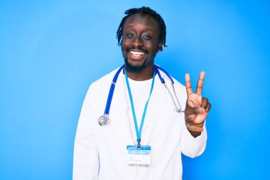 Saç örgülü, doktor steteskobu ve kimlik kartı takan, kameraya gülümseyen ve zafer işareti yapan Afro-Amerikan genç bir adam. İki numara.. 