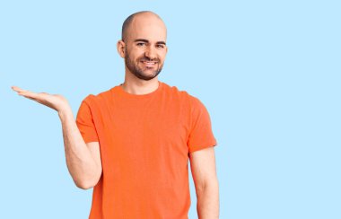 Genç yakışıklı adam rahat gömleğini indiriyor neşeli bir şekilde gülümsüyor ve avuç içi kameraya bakıyor.. 