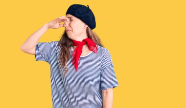 Fransız beresi ve çizgili tişört giyen genç, güzel sarışın bir kadın pis ve iğrenç bir koku alıyor. Nefesini burnunda tutuyor. Kötü kokuyor. 