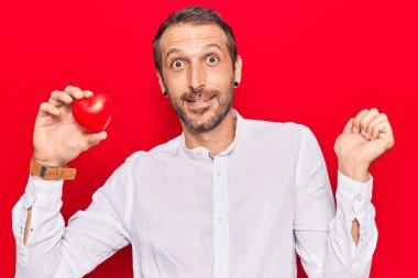 Kalbini tutan yakışıklı genç adam gururla haykırıyor, zaferi kutluyor ve başarıyı kollarını kaldırarak kutluyor. 