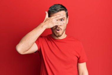 Yakışıklı beyaz adam, günlük kırmızı tişört giyiyor. Şoka giriyor, yüzünü ve gözlerini kapıyor, utangaç ifadesiyle parmaklarından bakıyor.. 