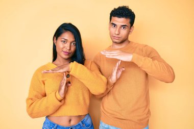 Güzel, Latin, genç bir çift, günlük giysiler giyip, el kol hareketleri yapıyorlar, hayal kırıklığına uğramış ve ciddi bir yüz ifadesi var. 