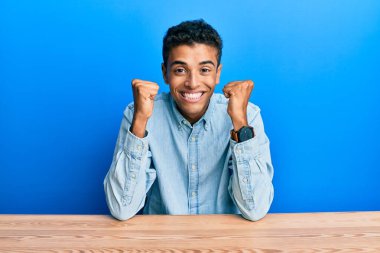 Genç, yakışıklı, Afro-Amerikalı, gündelik giysiler giymiş. Başarı için heyecanlı, kolları havada ve gözleri kapalı, zaferi kutlarken gülümsüyor. Kazanan konsept. 