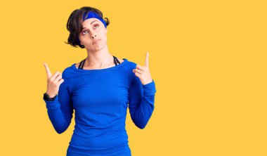 Kısa saçlı, antrenman kıyafeti giyen, üzgün ve üzgün görünen, yönünü parmaklarıyla gösteren mutsuz ve depresif bir kadın.. 