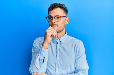 Sakallı, sıradan kıyafetler ve gözlük takan, el hareketleriyle sembolik silah tutan, cinayet silahlarıyla oynayan, sinirli yüzlü yakışıklı bir adam. 