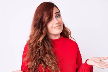 Gündelik kıyafetler giyen, elleri ve kolları havada, kafası karışmış genç ve güzel bir kadın. şüphe kavramı. 