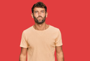 Yakışıklı, sakallı, sıradan bir tişört giyen kameraya bakıp havada öpücük yollayan yakışıklı ve seksi bir genç. aşk ifadesi. 