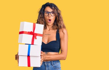 Dövmeli genç bir İspanyol kadın elinde hediyeler var. Korkmuş ve ağzı açık kalmış, şaşırmış ve şaşırmış. 