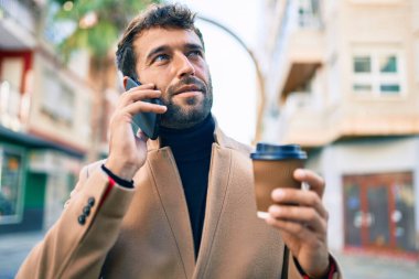 Zarif ceketli yakışıklı bir iş adamı. Açık havada akıllı telefon kullanıyor.