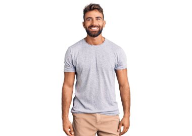 Yüzünde mutlu ve havalı bir gülümseme olan sıradan kıyafetler giyen genç İspanyol bir adam. şanslı kişi. 