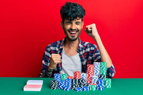 Poker Fişleri Kartlarla Masada Oturan Spanyol Genç Adam Kolları Havada — Stok fotoğraf