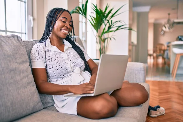 Νεαρή Αφροαμερικανή Γυναίκα Χαμογελά Ευτυχισμένη Δουλεύοντας Φορητό Υπολογιστή Στο Σπίτι — Φωτογραφία Αρχείου