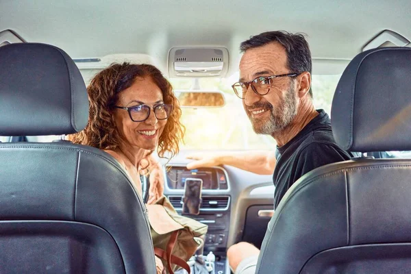 Middle age beautiful couple on vacation wearing glasses smiling happy driving car.