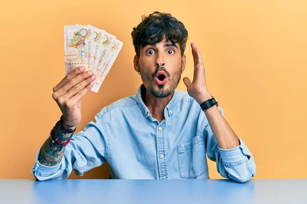 Young Hispanic Man Holding United Kingdom Pounds Banknotes Sitting Table — Stock Photo, Image