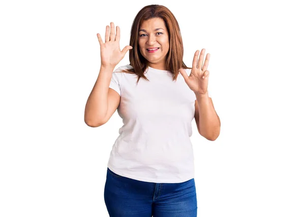 中年ラテン女性身に着けていますカジュアルホワイトTシャツショーと指差し込みで指番号9ながら笑顔自信と幸せ — ストック写真