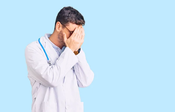 Joven Guapo Con Oso Vistiendo Uniforme Médico Con Expresión Triste —  Fotos de Stock