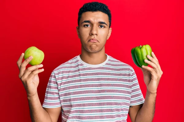 緑のリンゴと唐辛子を持っている若いアラブ人の男は落ち込んでおり 苦痛のために心配し 怒って恐れて泣いています 悲しい表情 — ストック写真