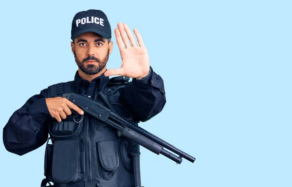 Ung Latinamerikan Man Bär Polisuniform Håller Hagelgevär Med Öppen Hand — Stockfoto