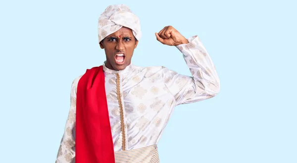 伝統的なシャーワニを身に着けているアフリカのハンサムな男は怒りで叫んでいる間服が怒っていると怒っている拳を上げるのを見ました 怒りと攻撃的な考え方 — ストック写真
