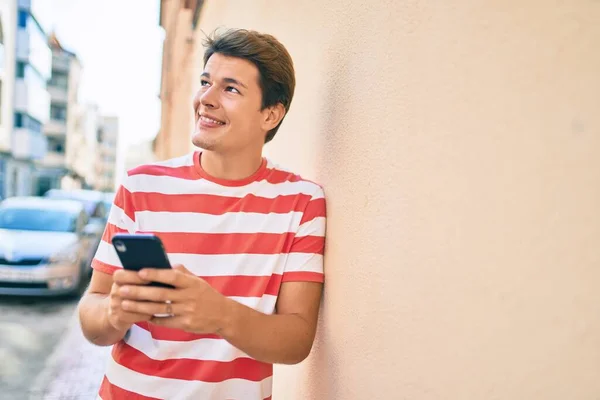Mladý Kavkazský Muž Usměvavý Šťastný Pomocí Smartphonu Městě — Stock fotografie
