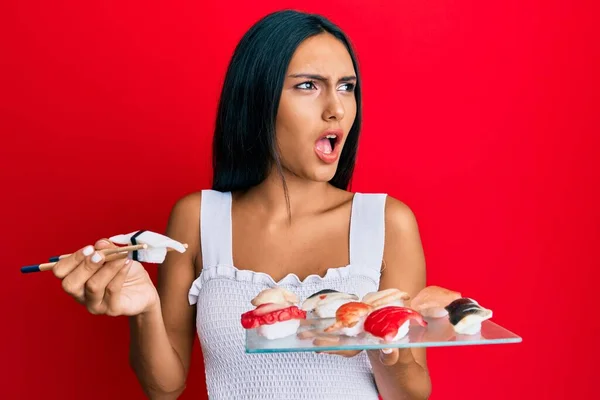 Mujer Morena Joven Comiendo Sushi Pez Mantequilla Usando Palillos Enojados — Foto de Stock