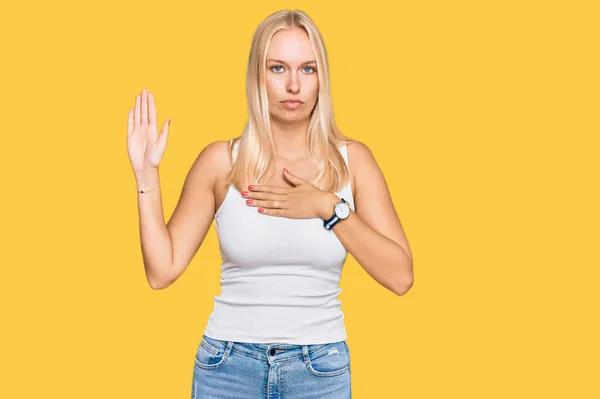 Młoda Blondynka Luźnym Stylu Koszulą Bez Rękawów Przeklinając Dłonią Piersi — Zdjęcie stockowe