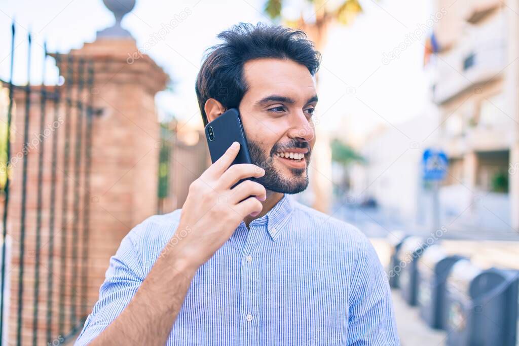 Young hispanic man smiling happy talking on the smartphone at city.