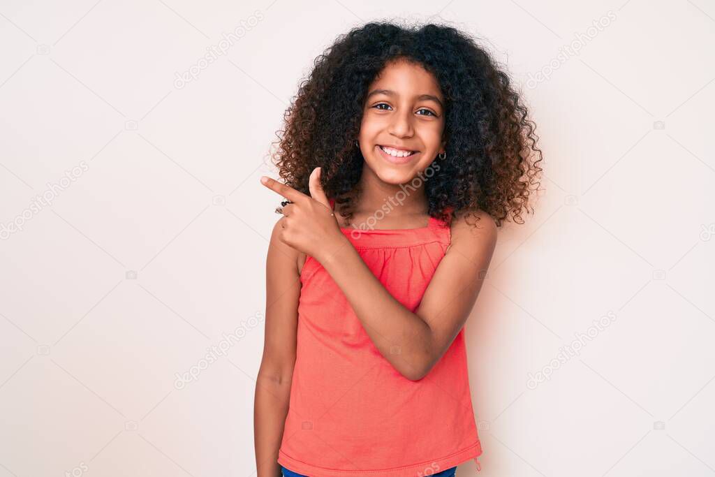 African american child with curly hair wearing casual clothes smiling cheerful pointing with hand and finger up to the side 