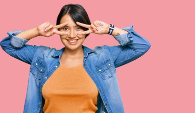 Kısa saçlı, güzel İspanyol bir kadın. Sıradan bir kot ceket giyiyor. Barış sembolü yapıyor. 