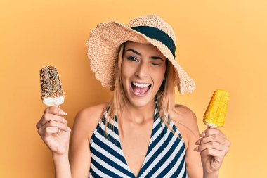 Yaz tarzı giyinen güzel sarışın kadın elinde dondurmayla kameraya bakıyor. Seksi bir ifadeyle, neşeli ve mutlu bir yüzle.. 