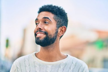 Genç Afrikalı Amerikalı adam gülümseyerek şehirde mutlu mesut duruyor..