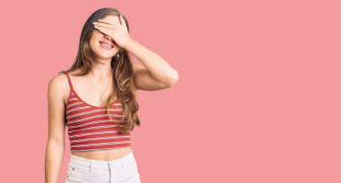 Gündelik kıyafetler giyen güzel beyaz bir kadın. Gülümsüyor ve elleri yüzünde, şaşırmak için gözleri kapatıyordu. kör kavram. 