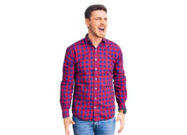 Ayılı yakışıklı genç adam rahat gömleği giyiyor kızgın ve kızgın bağırıyor sinirli ve öfkeli, öfkeyle bağırıyor. öfke ve agresif konsept. 