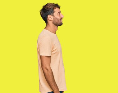 Sakallı, sıradan tişörtler giyen, rahat bir görünüm takınan, doğal yüzlü ve kendine güvenen genç bir adam.. 